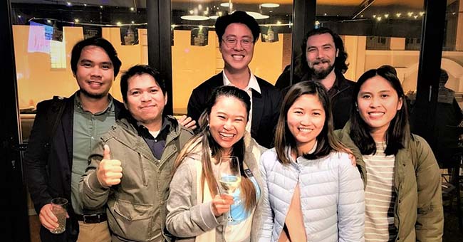 Sheela standing together with six of her coworkers at a Planit company party