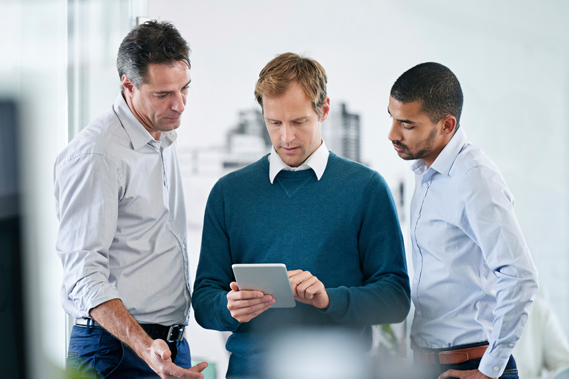 Three men gathered around a tablet device